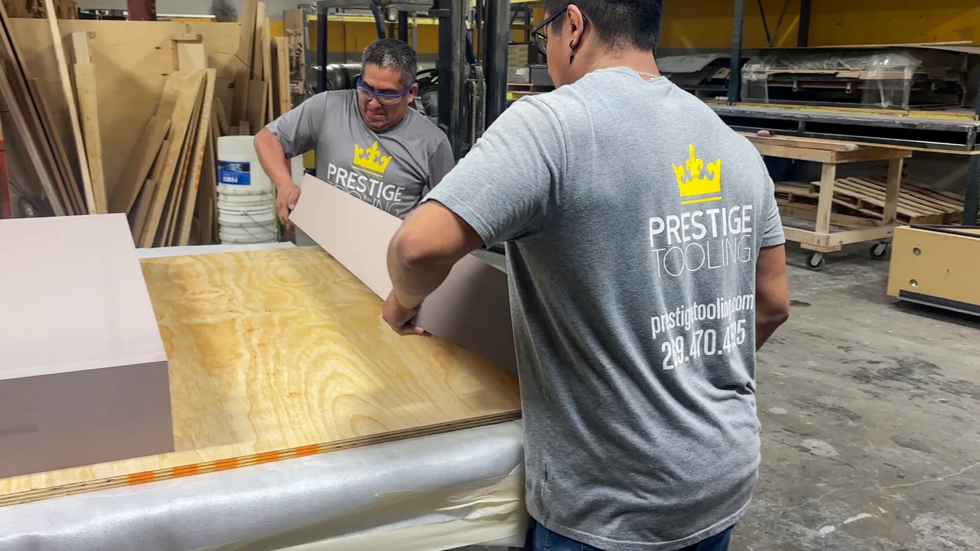 Two Prestige employees handling a CNC-machined pattern in the shop