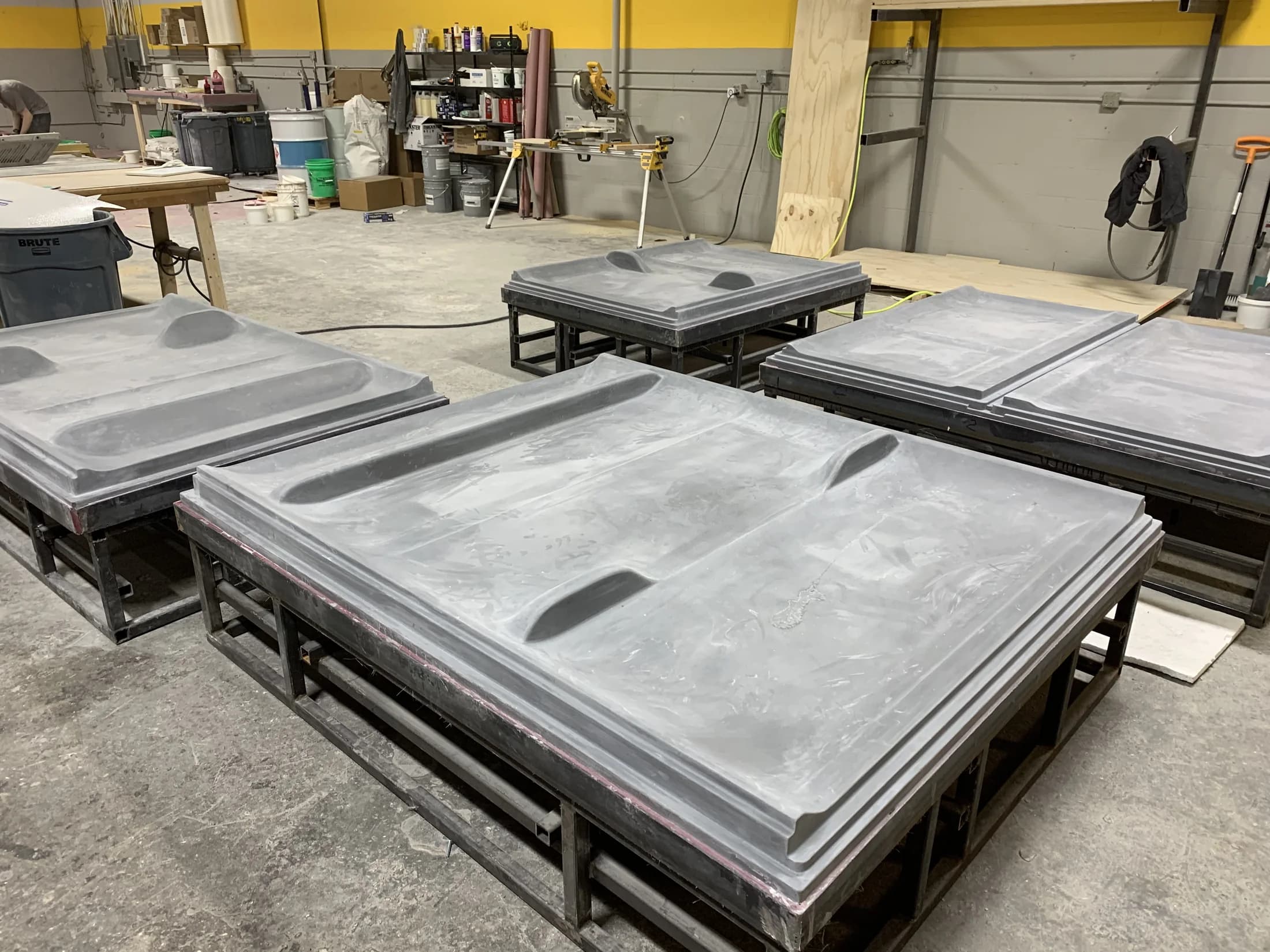 Multiple completed thermoforming shower-wall surround molds on steel support frames