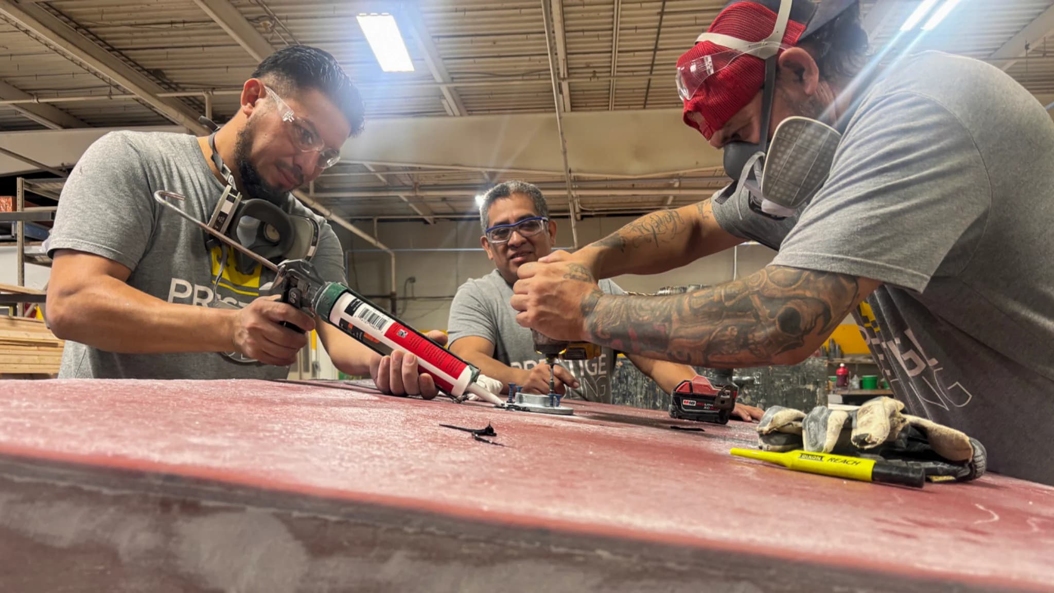 Three Prestige employees fastening hardware to a red thermoforming mold