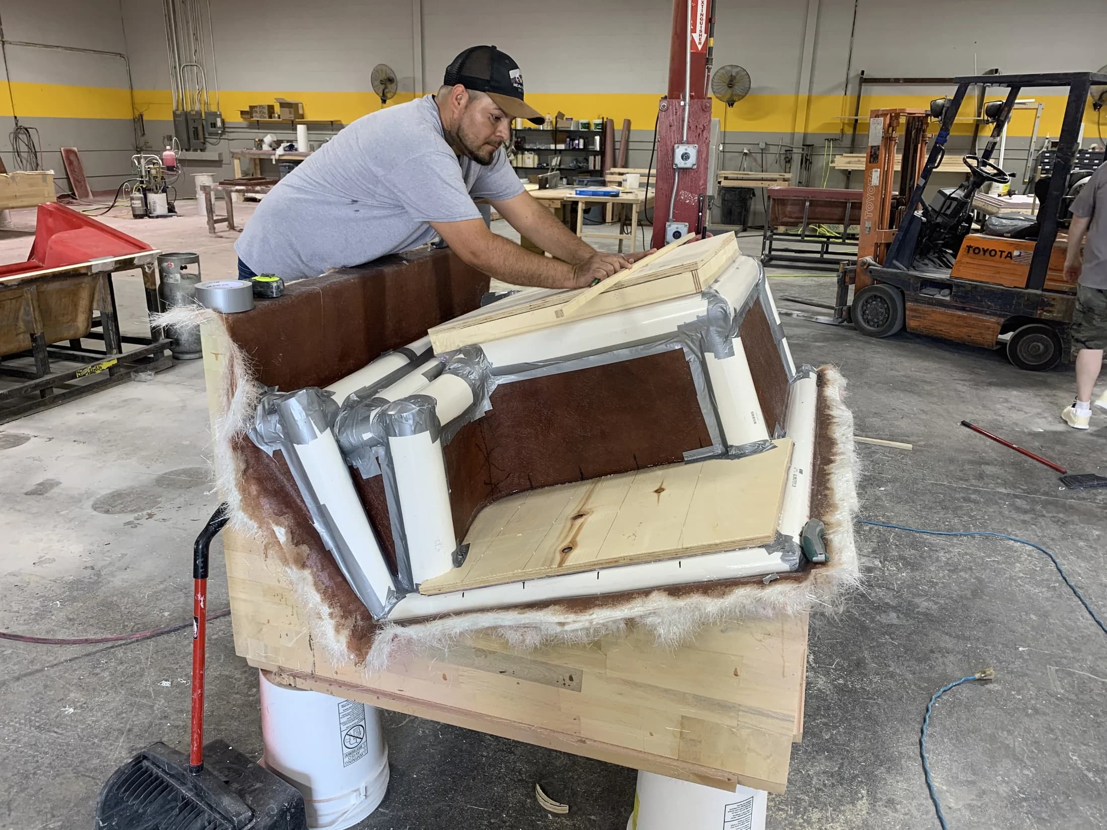 Prestige employee tubing a thermoforming bathtub mold during production